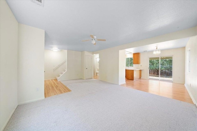 carpeted living room with ceiling fan with notable chandelier and a textured ceiling