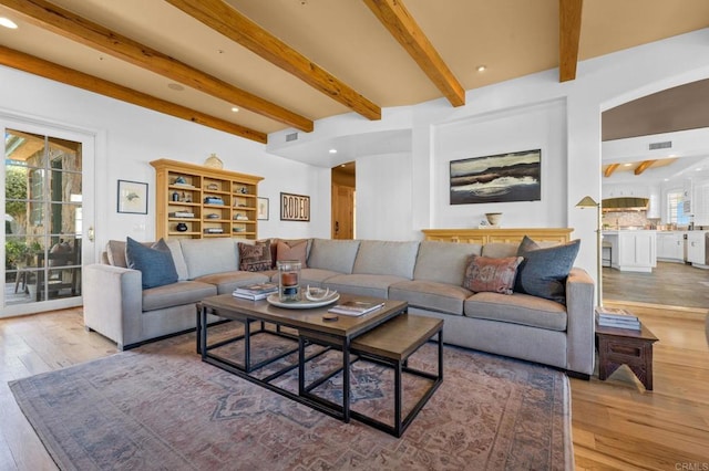 living room with beamed ceiling and light hardwood / wood-style flooring