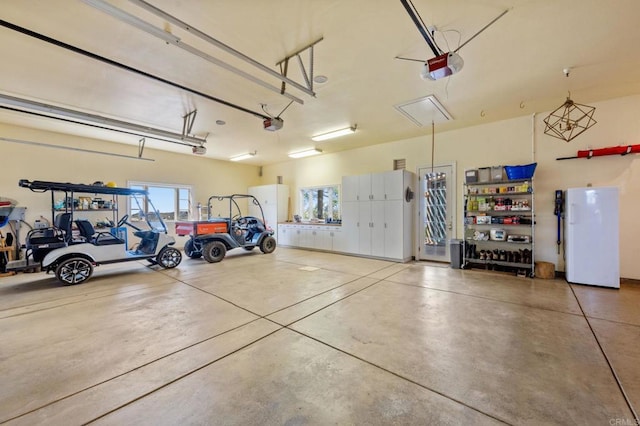 garage featuring white fridge and a garage door opener