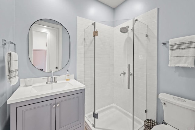 bathroom featuring vanity, toilet, and a shower with shower door