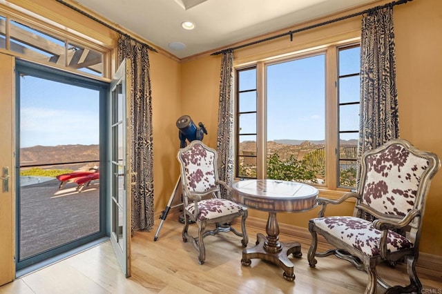 sitting room featuring a mountain view, a healthy amount of sunlight, light wood-type flooring, and crown molding