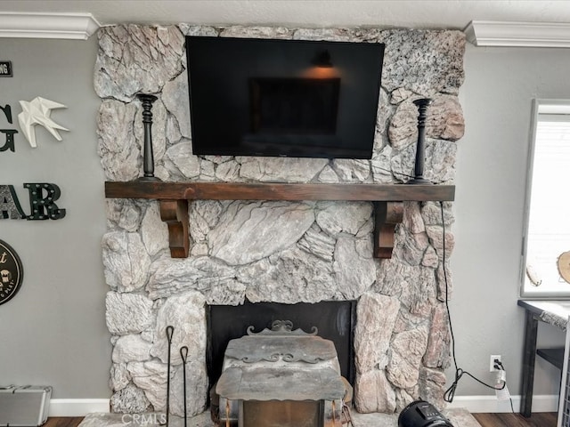 room details with crown molding, hardwood / wood-style flooring, and a stone fireplace