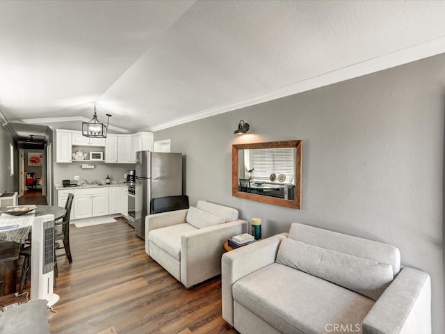 living room with lofted ceiling, dark wood-type flooring, crown molding, and a chandelier