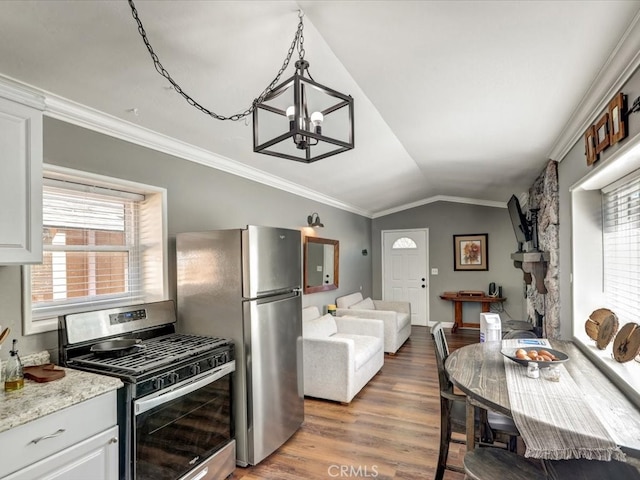 kitchen with hanging light fixtures, appliances with stainless steel finishes, white cabinetry, hardwood / wood-style flooring, and vaulted ceiling