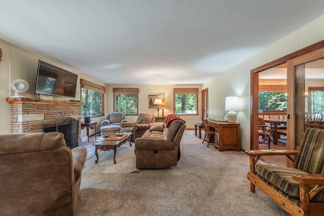 carpeted living room with a stone fireplace