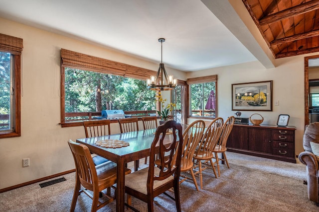 carpeted dining area featuring a healthy amount of sunlight, wooden ceiling, a chandelier, and lofted ceiling with beams