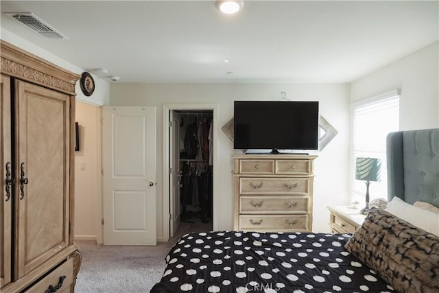 carpeted bedroom with a walk in closet and a closet