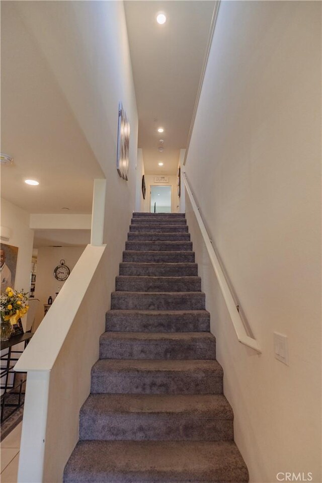 stairway featuring crown molding and tile patterned flooring