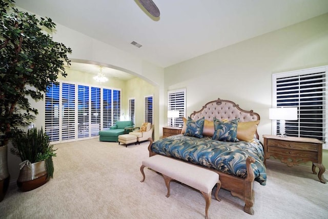 carpeted bedroom featuring ceiling fan with notable chandelier