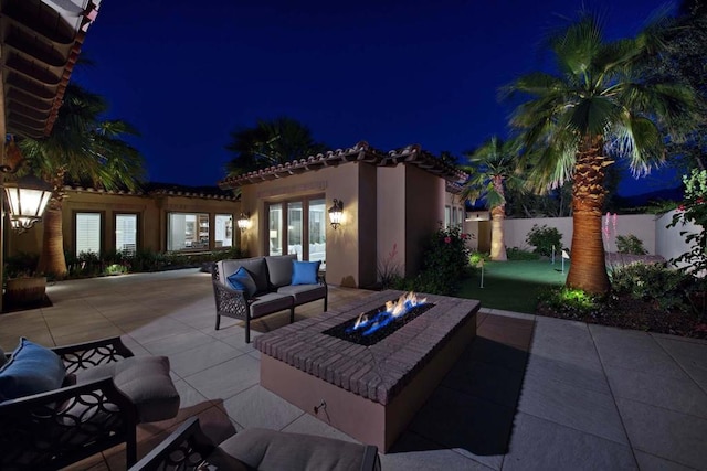 patio at night with an outdoor living space with a fire pit and french doors