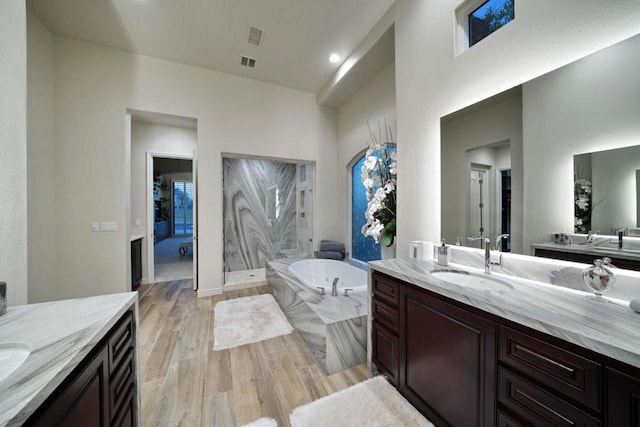 bathroom with a bathing tub, vanity, a high ceiling, and hardwood / wood-style flooring