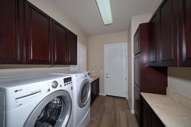 washroom featuring cabinets, light hardwood / wood-style flooring, and washing machine and clothes dryer