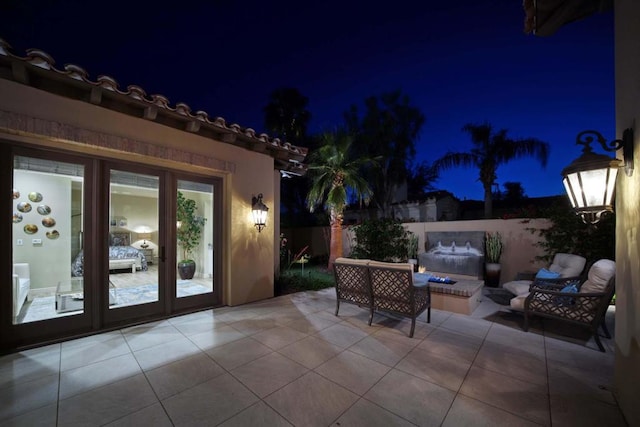 patio at night featuring french doors and an outdoor living space with a fire pit