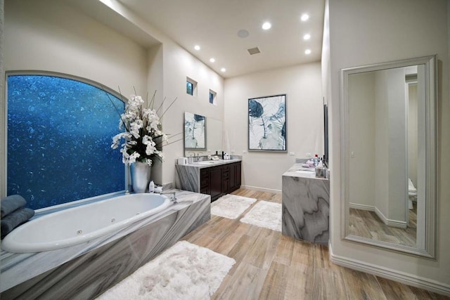 bathroom with vanity, a bathtub, toilet, and wood-type flooring