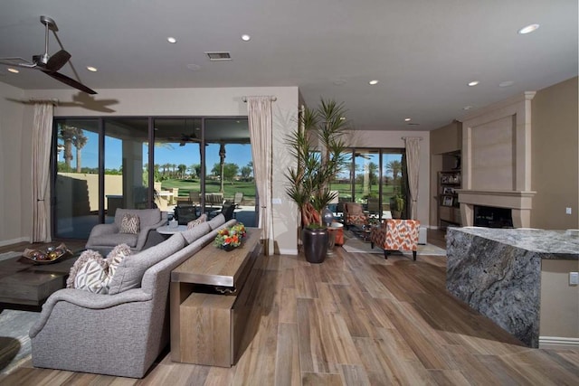 living room featuring a fireplace, light wood-type flooring, and ceiling fan