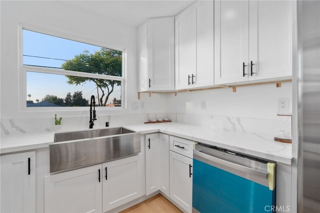 kitchen featuring light stone countertops, stainless steel appliances, sink, light hardwood / wood-style flooring, and white cabinetry