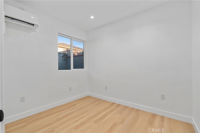 empty room featuring a wall mounted air conditioner and hardwood / wood-style flooring