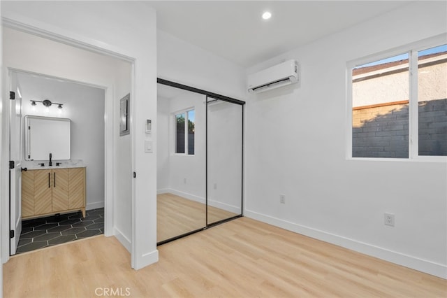 bedroom featuring a closet, light hardwood / wood-style floors, an AC wall unit, and multiple windows