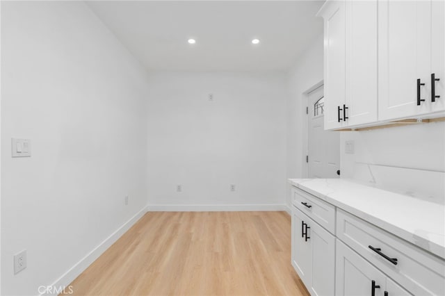 interior space featuring light wood-type flooring, white cabinetry, and light stone counters