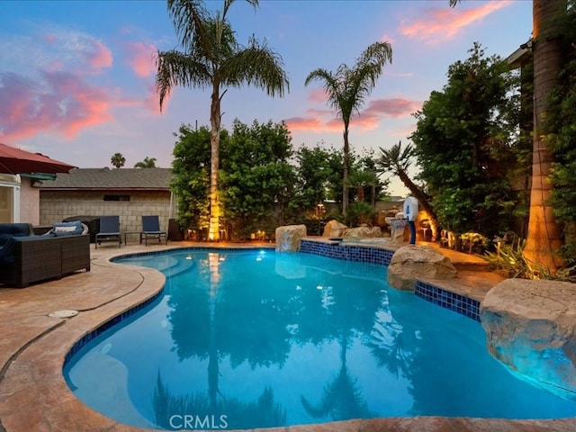 pool at dusk featuring a patio area