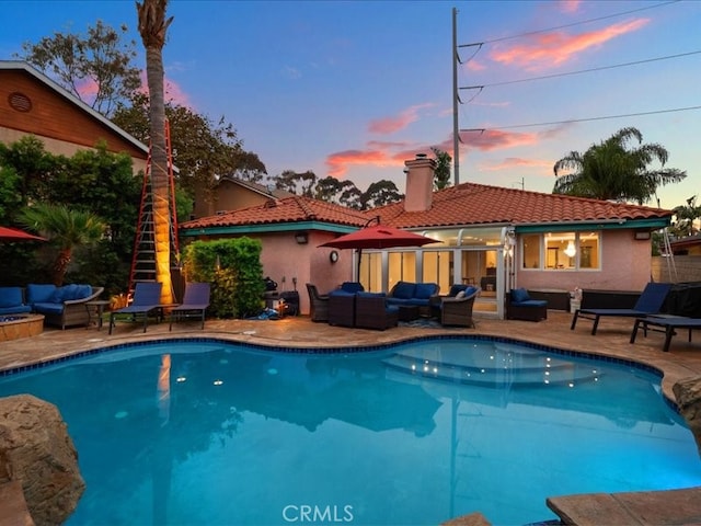 pool at dusk with an outdoor living space and a patio area