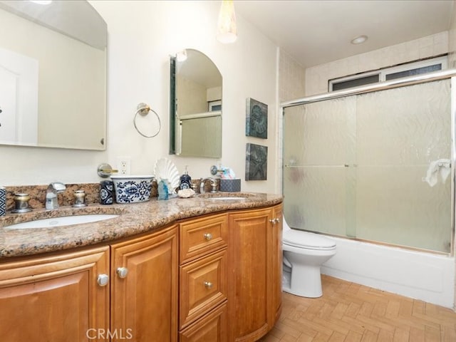 full bathroom featuring vanity, parquet floors, combined bath / shower with glass door, and toilet