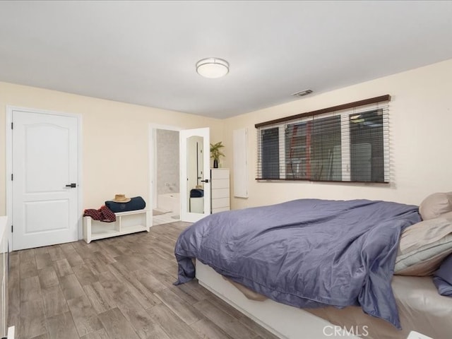 bedroom featuring hardwood / wood-style flooring and ensuite bath