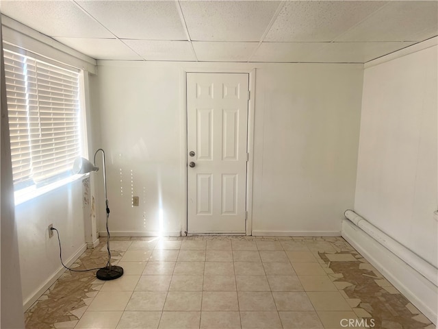 unfurnished room featuring a drop ceiling and light tile patterned floors