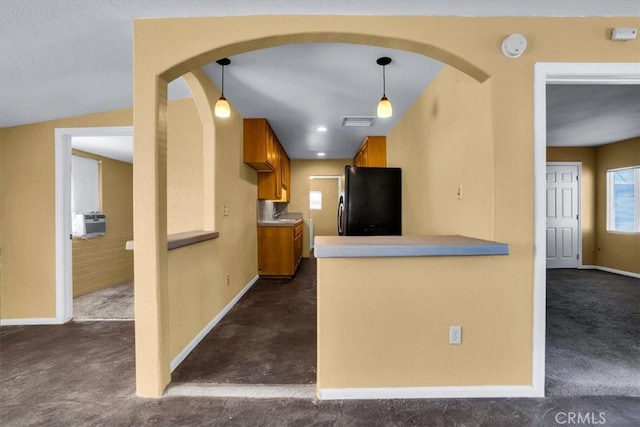 kitchen with kitchen peninsula, vaulted ceiling, pendant lighting, dark carpet, and black refrigerator