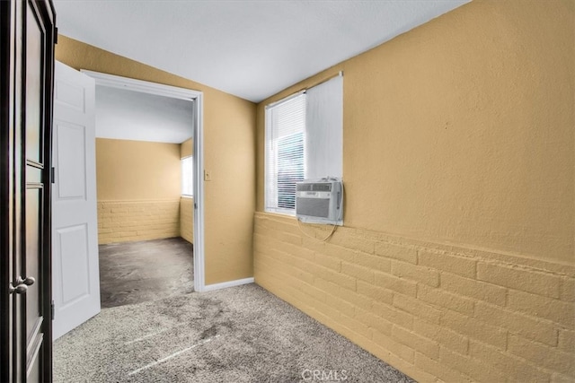 carpeted empty room featuring cooling unit, brick wall, and lofted ceiling