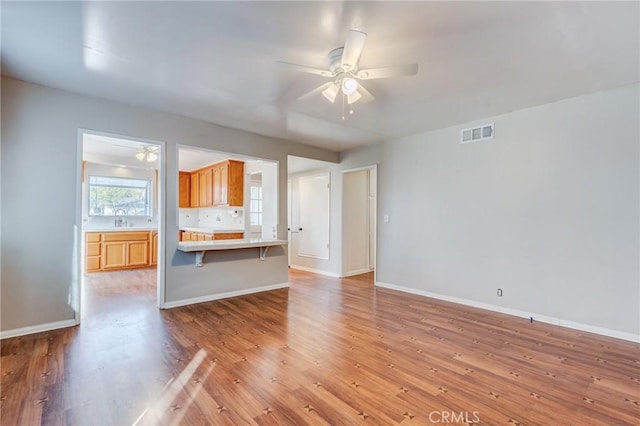 unfurnished living room with ceiling fan, sink, and light hardwood / wood-style flooring