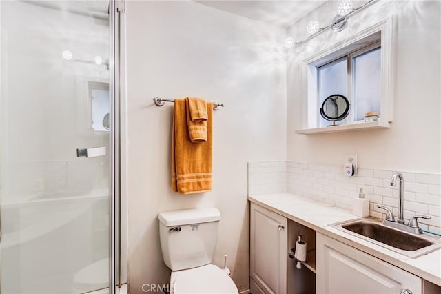 bathroom with a shower with door, vanity, backsplash, and toilet