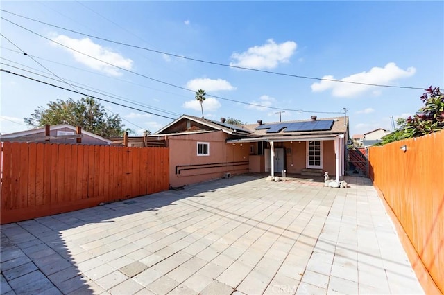 rear view of house with a patio area and solar panels