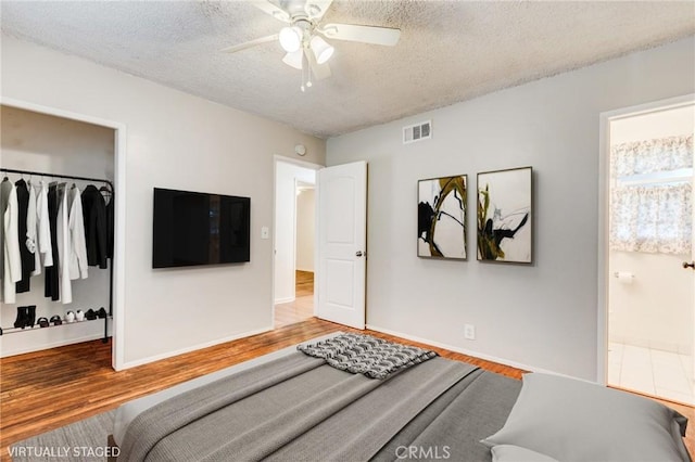 bedroom featuring connected bathroom, hardwood / wood-style flooring, a closet, and a textured ceiling