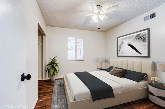 bedroom with ceiling fan, dark hardwood / wood-style floors, and a textured ceiling