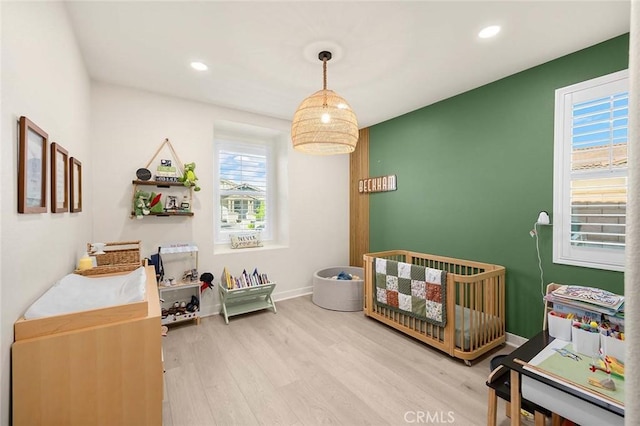 bedroom with a nursery area and hardwood / wood-style flooring