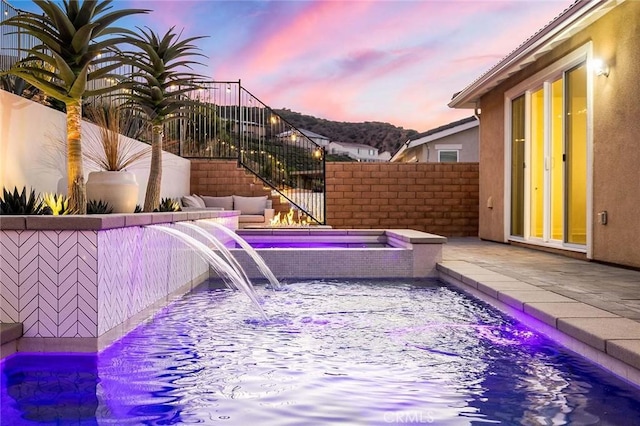 pool at dusk with an in ground hot tub and pool water feature