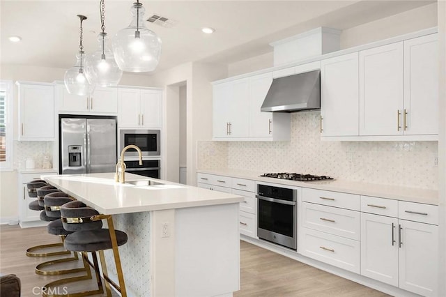 kitchen with white cabinets, stainless steel appliances, and wall chimney exhaust hood