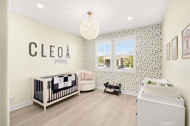 bedroom featuring a crib and light hardwood / wood-style flooring