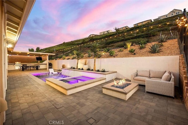 view of pool with a patio, pool water feature, a hot tub, and exterior kitchen