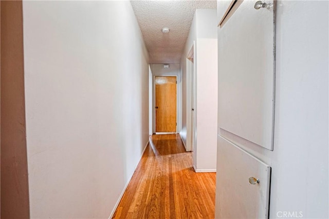 hallway with a textured ceiling and hardwood / wood-style flooring