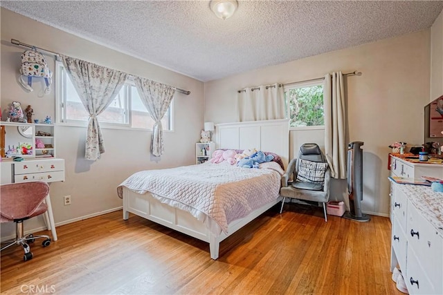 bedroom featuring a textured ceiling, light hardwood / wood-style floors, and multiple windows