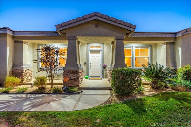 view of exterior entry featuring a lawn