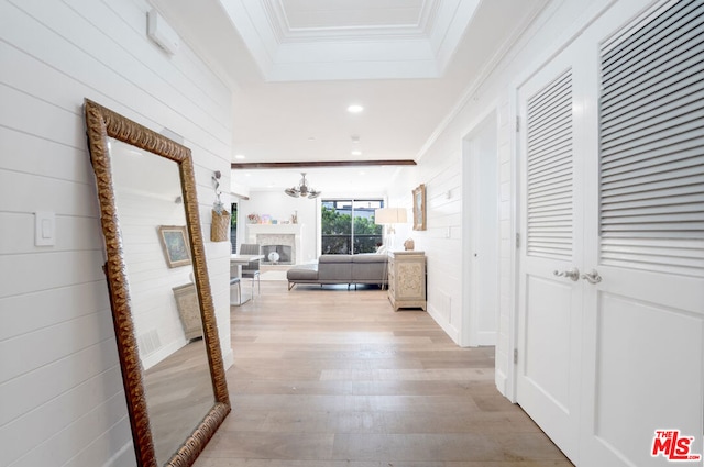 corridor featuring crown molding, a raised ceiling, and light hardwood / wood-style flooring