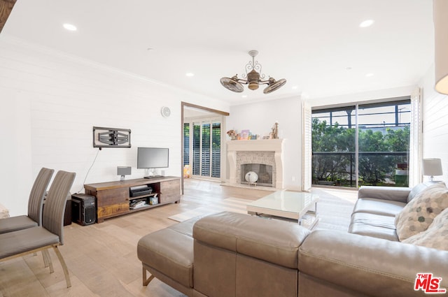 living room featuring ornamental molding, light wood-type flooring, and a wealth of natural light