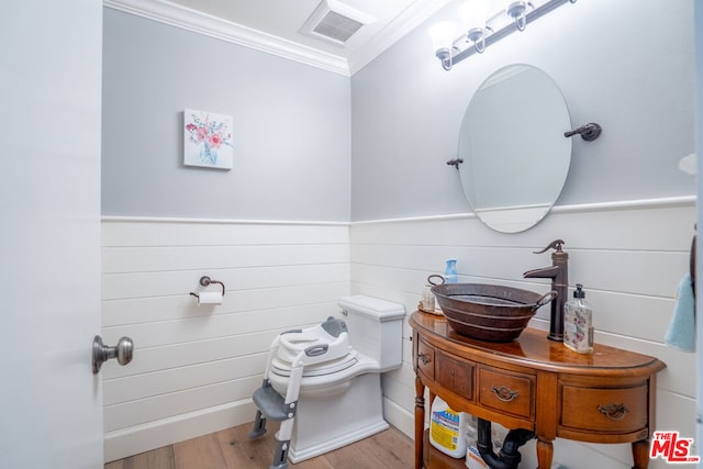 bathroom featuring vanity, ornamental molding, wood-type flooring, and toilet