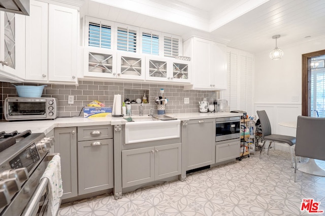 kitchen featuring appliances with stainless steel finishes, white cabinetry, tasteful backsplash, and pendant lighting