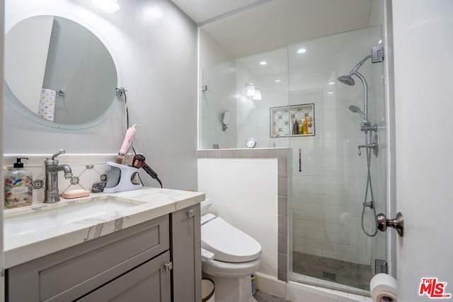 bathroom featuring toilet, an enclosed shower, and vanity