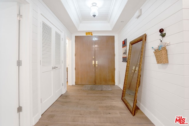 corridor featuring a tray ceiling and light wood-type flooring