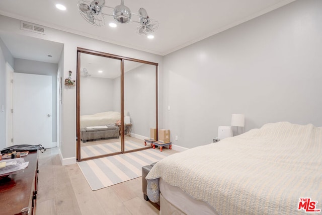 bedroom with ornamental molding, light hardwood / wood-style flooring, and a closet